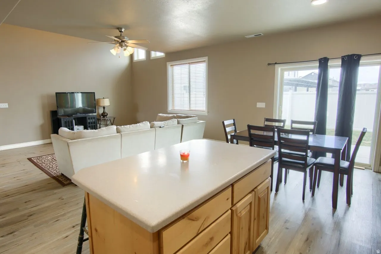 Open-concept living area featuring wood-finish flooring, a ceiling fan, and a kitchen island with a light-colored countertop