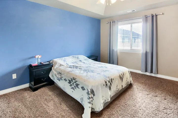 Tray ceiling with a ceiling fan, window with blinds, and wall-to-wall carpeting