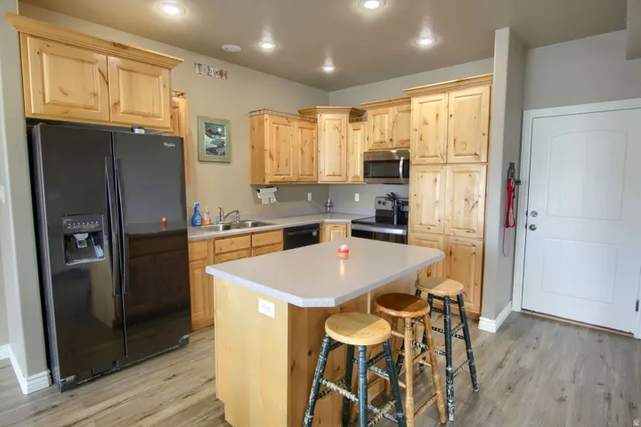 Kitchen featuring wood-finish cabinetry, a central island with a countertop, recessed lighting, and wood-finish flooring