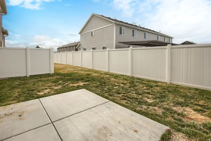 Fenced backyard featuring a concrete patio and established turf