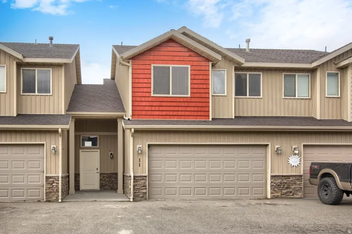 Multi-level exterior featuring tan siding with red accent panels and stone veneer detailing