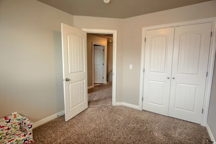 Neutral tone wall paint, carpeted flooring, white interior doors with paneled detailing, white trim