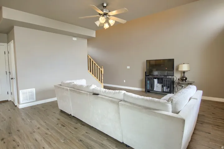 Wood-finish flooring, vaulted ceiling with a ceiling fan, and a staircase with wood railings