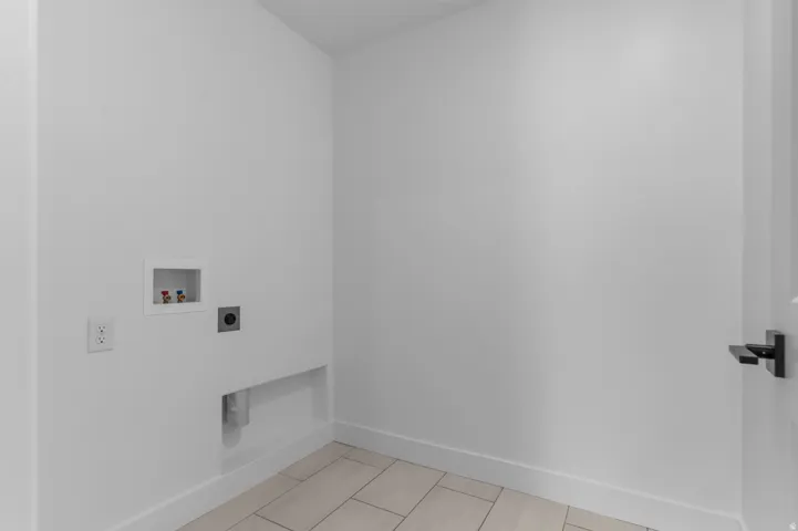 Dedicated laundry area with light-toned rectangular tile flooring