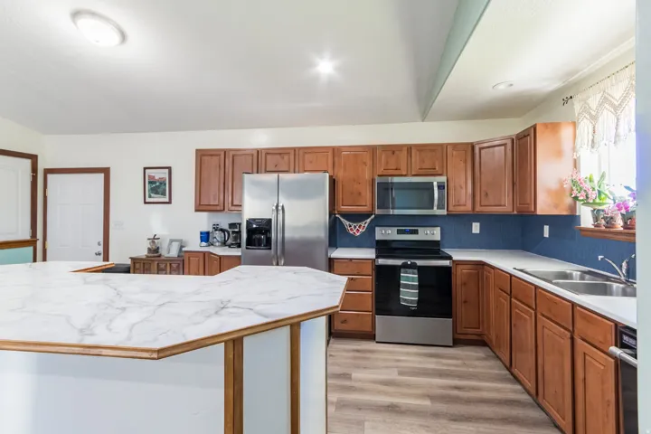 Kitchen featuring wood-finish flooring, white countertops, wood cabinetry, and stainless steel appliances