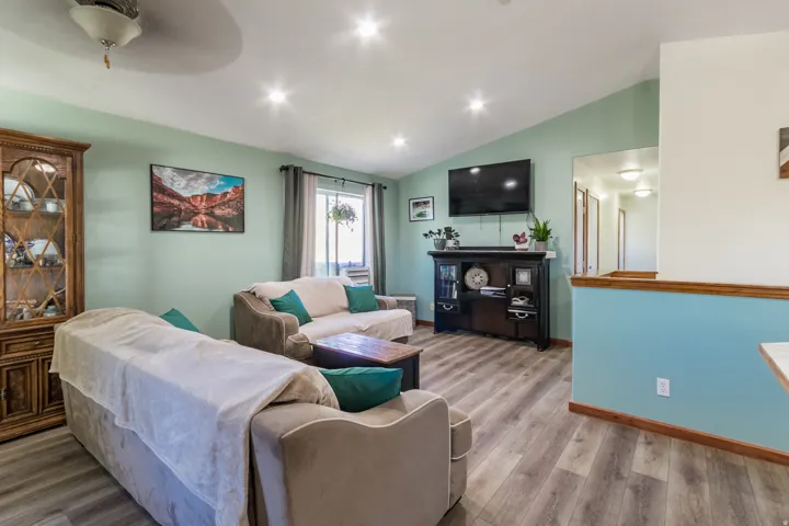 Living area with wood-finish flooring, vaulted ceiling, and recessed lighting