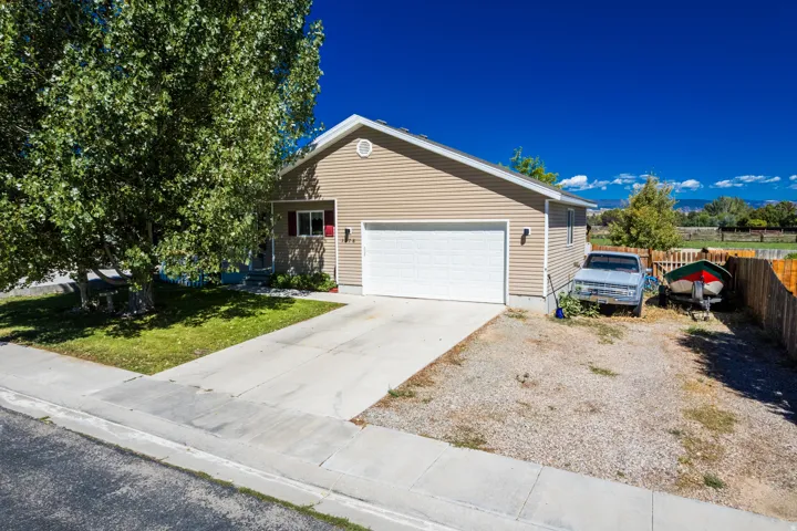 Single-story residence featuring tan horizontal siding, an attached garage, and a concrete driveway