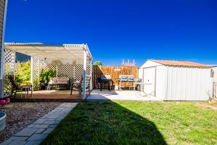 Pergola-covered deck, concrete patio, wood privacy fence, metal storage shed, and a paver walkway