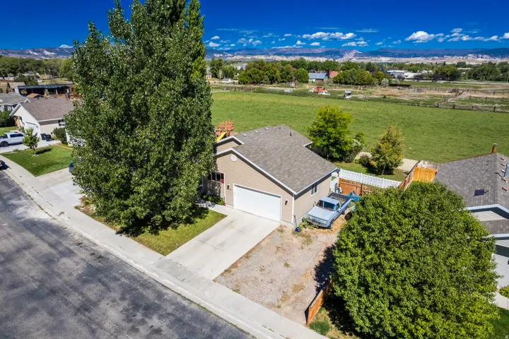 Single-story residence with an attached garage, paved driveway, and mature landscaping