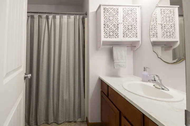 Vanity with an integrated sink, polished chrome faucet, wood-finish cabinetry, and overhead decorative wall storage