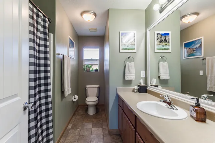 Vanity with integrated sink and chrome faucet, large framed mirror, built-in cabinetry, flush-mount ceiling lighting, and a window with blinds