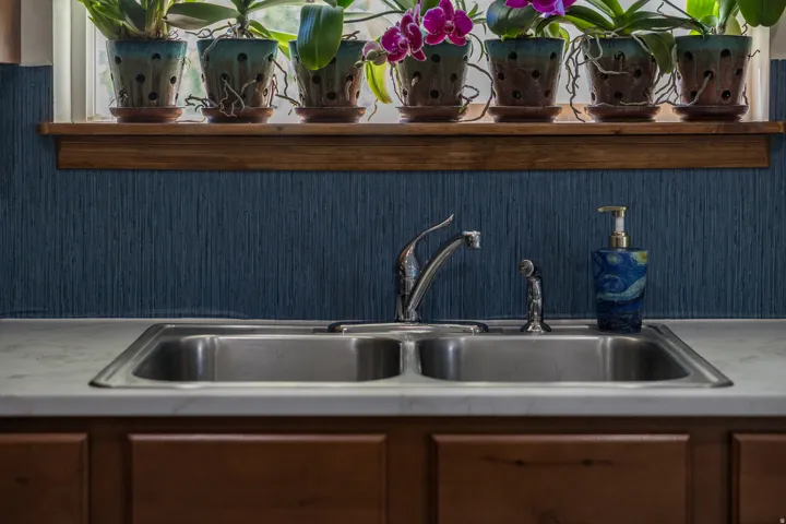 Stainless steel double basin sink with chrome faucet, set into a light-toned countertop