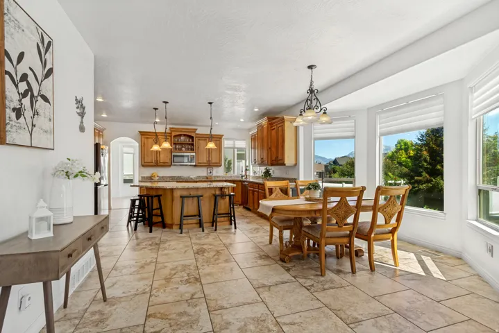 Expansive tiled flooring throughout, kitchen island with built-in seating, light wood cabinetry, recessed lighting, and large bay windows