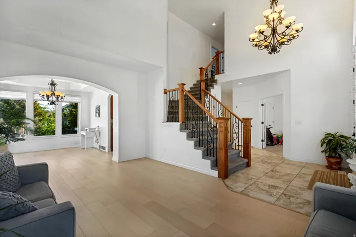 Two-story entryway with a grand staircase featuring wrought iron balusters and wood handrails