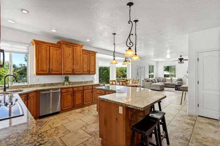 Open concept kitchen featuring wood cabinetry, granite countertops, and stainless steel appliances