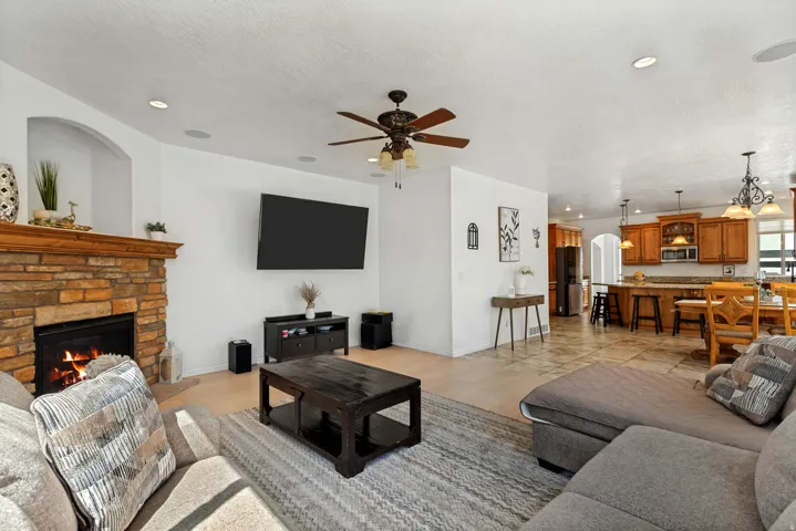 Living room featuring a stone-clad fireplace with wood mantle, light wood-finish flooring, and recessed lighting
