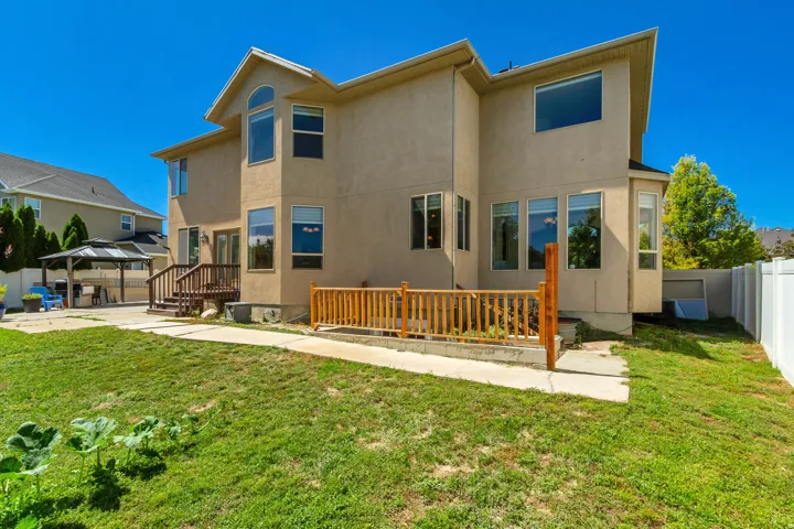 Stucco exterior featuring multiple windows, a rear wood deck, and a white privacy fence