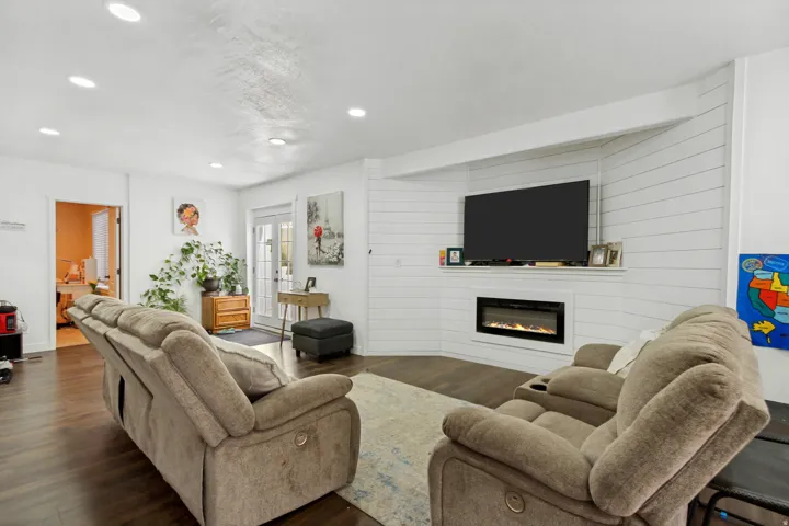 Living area featuring wood-finish flooring, recessed lighting, and a corner fireplace with a mounted television