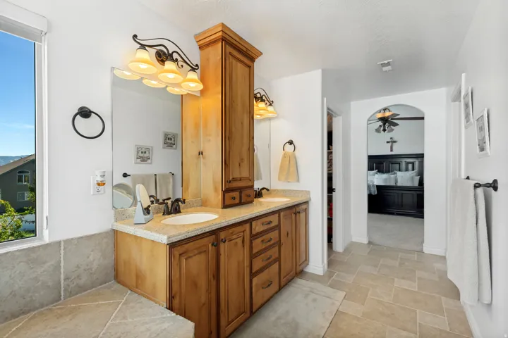 Dual vanity with wood-finish cabinetry, integrated sinks, and polished countertops