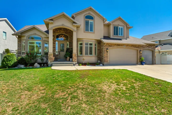 Stucco exterior with stone accents, arched entryway, bay windows, and attached two-car garage