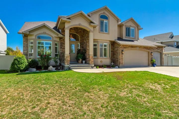 Stucco exterior with stone accents, arched entry, bay window, and a two-car garage