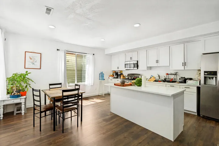 Kitchen featuring white cabinetry, stainless steel appliances, solid surface countertops, and wood-finish flooring