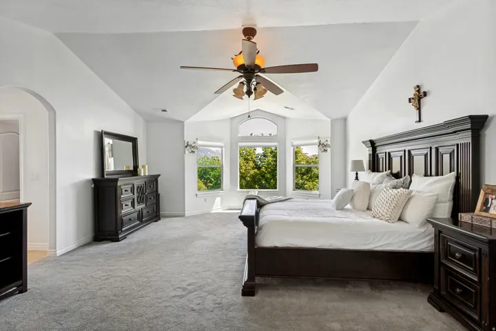 Vaulted ceiling with a ceiling fan, arched doorway, and bay window