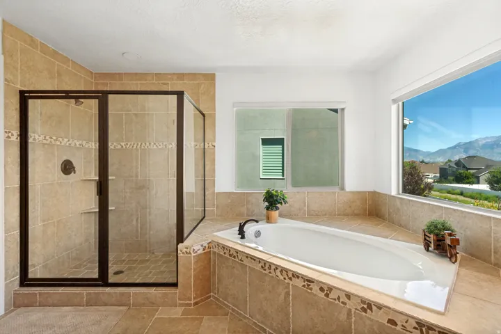 Tiled walk-in shower with a glass enclosure, built-in shelving, and a separate built-in soaking tub
