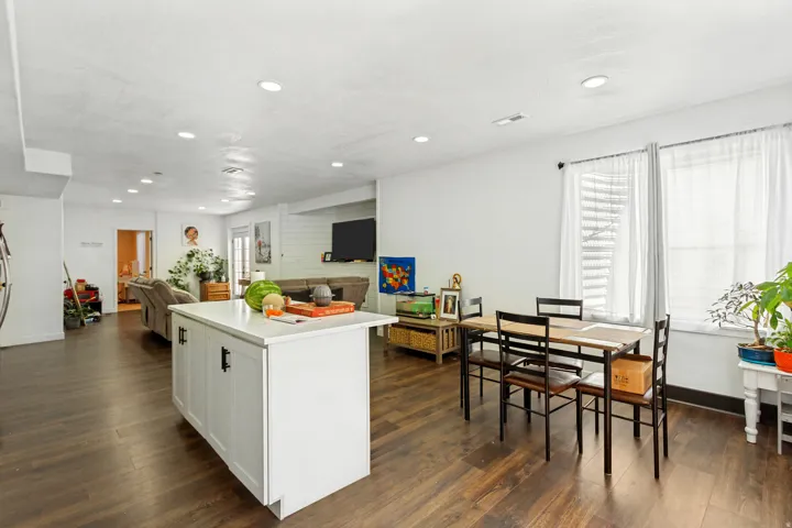 Open-concept living space with dark wood-finish flooring, recessed lighting, and white walls
