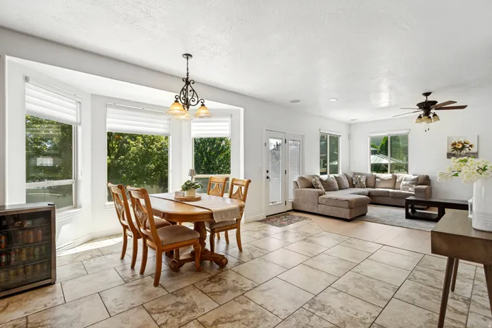 Bay window with multiple glass panels, tiled flooring, pendant lighting fixture, wood-finish flooring, and a ceiling fan