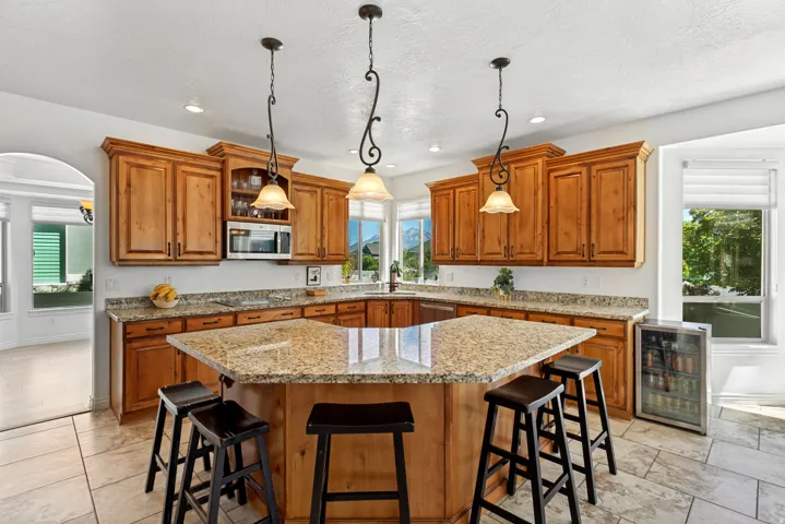 Kitchen featuring wood cabinetry, granite countertops, tile flooring, and a large central island with pendant lighting