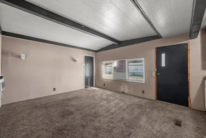Ceiling with exposed beams, light-colored walls, and carpeting