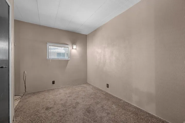 Textured walls with neutral paint, wall-mounted light fixture, and window with blinds
