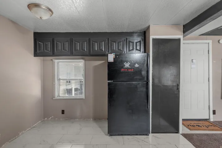 Recessed overhead cabinetry, single-pane window, flush mount ceiling light, and white tile flooring