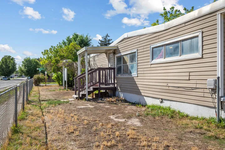 Siding exterior with multiple windows, covered porch entry, and chain-link fencing