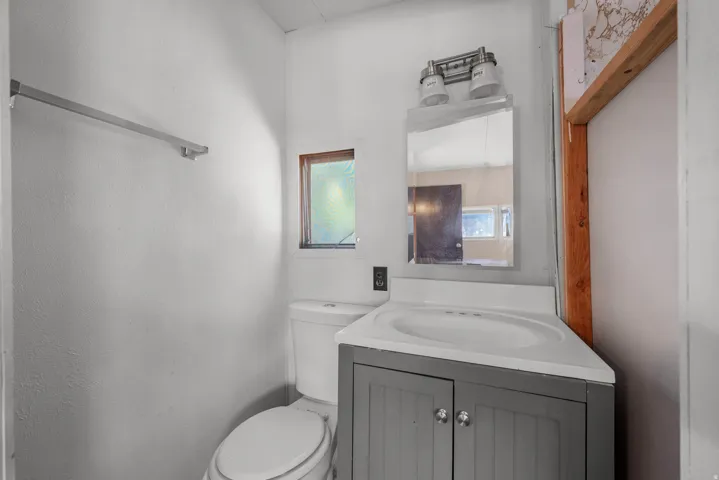White rectangular sink with a gray base cabinet, illuminated by a vanity light fixture