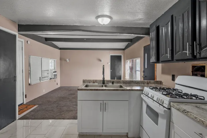Kitchen featuring granite-finish countertops, stainless steel sink, white range, and dark upper cabinetry