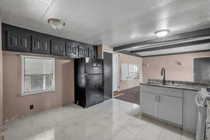 Kitchen featuring new tile flooring, white lower cabinetry, an undermount sink, and a high-arc faucet