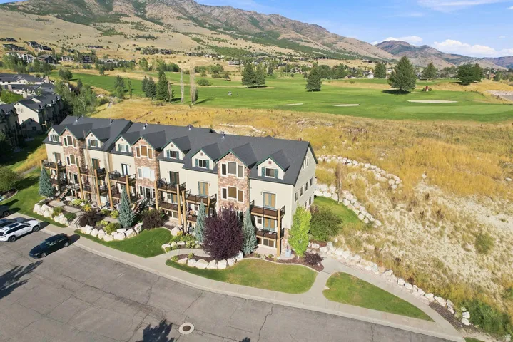 Townhome complex featuring stone and siding exterior, multiple balconies, landscaped grounds, and a mountain backdrop