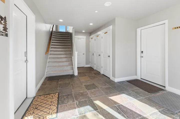 Slate tile flooring, recessed lighting, white interior doors, and a carpeted staircase with a wood handrail