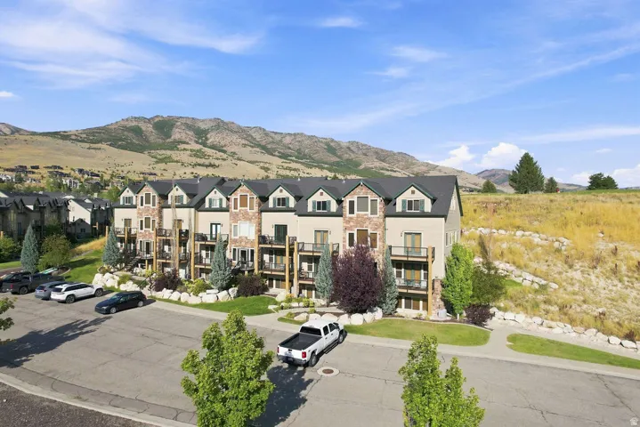 Multi-level property featuring a stone and siding exterior, private balconies, and landscaped grounds