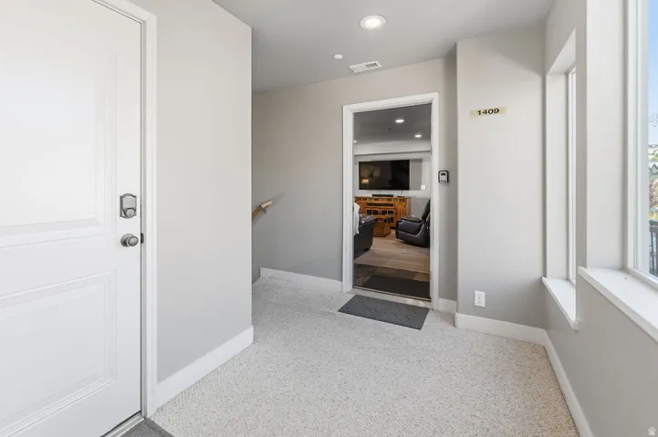 Entryway featuring light-toned carpeting, a white paneled door with smart lock, and neutral wall paint