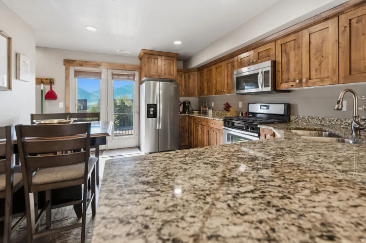 Kitchen featuring granite countertops, wood cabinetry, stainless steel appliances, and a double glass door