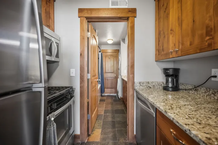 Stainless steel appliances, wood-finish cabinetry, granite countertops, and slate-finish floor tiling