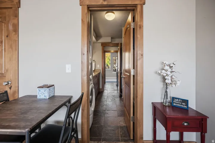 Hallway with stone-look tile flooring, light-colored walls, and solid wood doors with matching trim