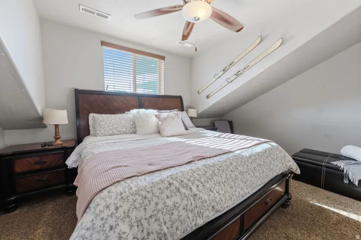 Window with horizontal blinds, ceiling fan with integrated lighting, and sloped ceiling details