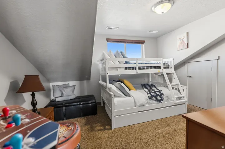 Sloped ceilings with recessed lighting, light-toned carpeting, and a window with wood-finish trim