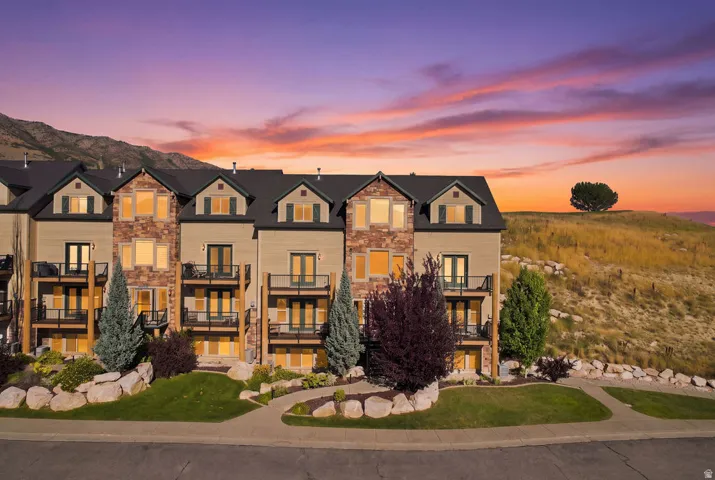 Multi-level townhome exterior featuring stone and siding finishes, multiple balconies with dark railings, and gable dormers