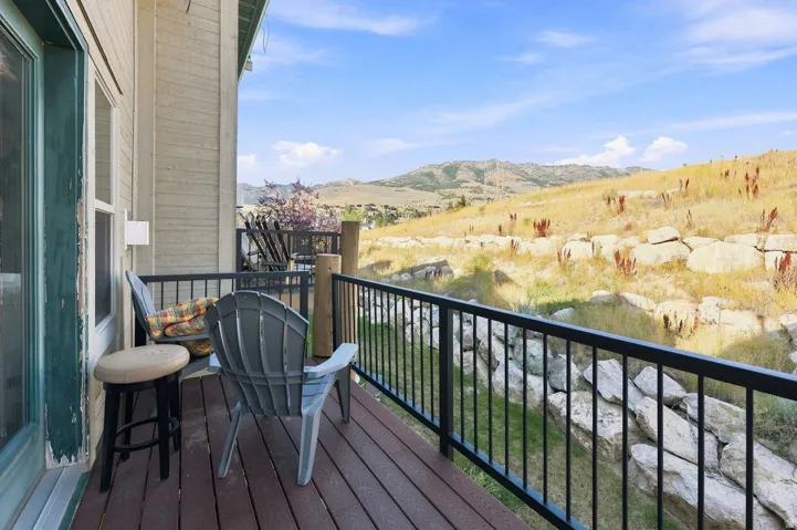 Outdoor balcony featuring composite decking, black metal railings, and a natural, arid landscape backdrop