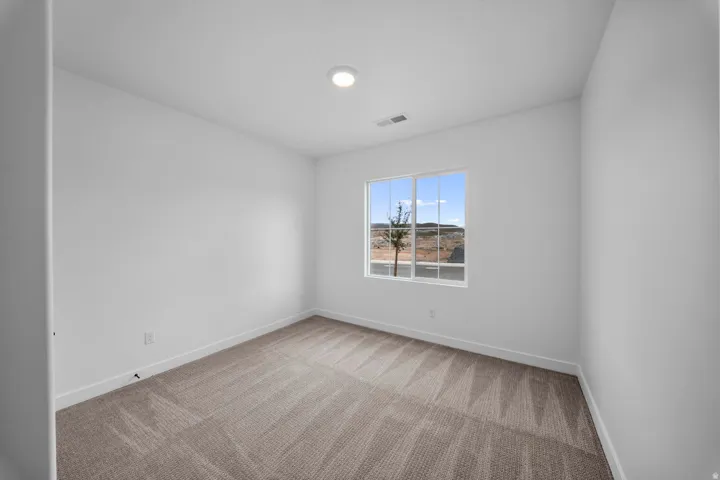 Neutral-toned carpet flooring, white walls, recessed ceiling light, and a window with a white frame
